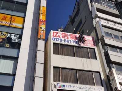 2024年12月16日　埼玉県熊谷市　駅前の高所壁面看板に広告募集シート貼り